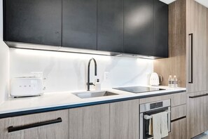 A modern kitchen with a double sink, a toaster, a coffee maker, and wooden cabinets. - 72 Park by Mia Casa (Miami Beach)