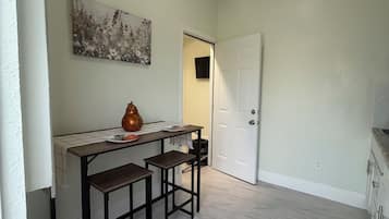 A kitchen with a white countertop, two bar stools, a vase, and a painting on the wall.
