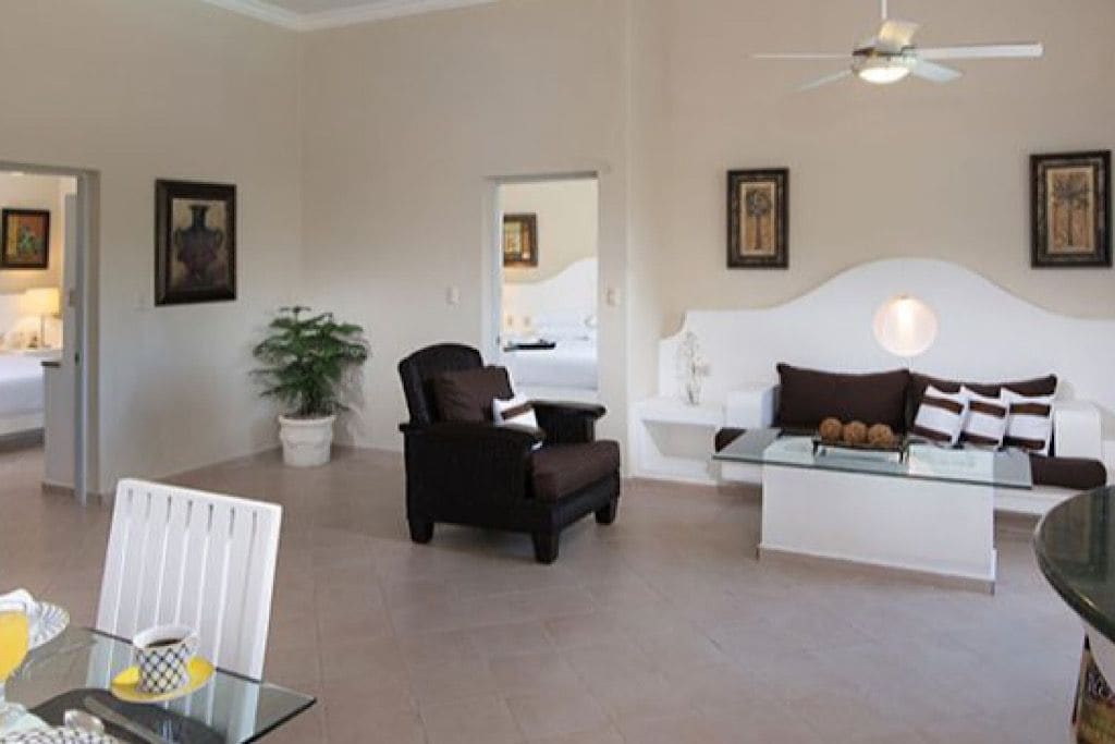 A modern living room with a glass coffee table, a sofa, a chair, and a ceiling fan.