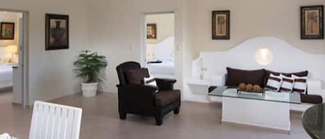 Una sala de estar moderna con una mesa de centro de vidrio, un sofá, un sillón y un ventilador de techo.