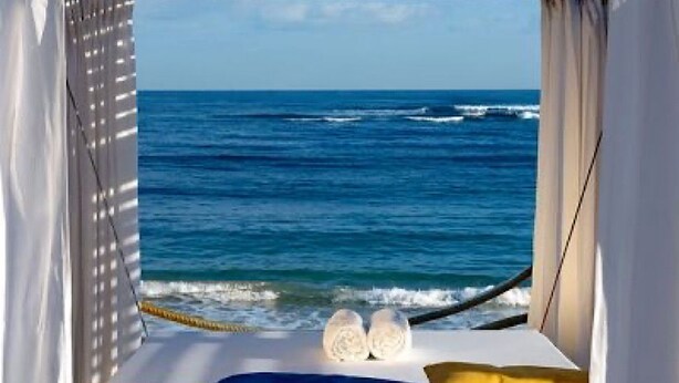 Una cama con vista al océano, una cuerda y dos almohadas.