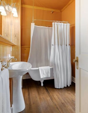 A bathroom with a white bathtub, a sink, and a shower curtain.