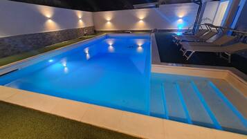 Ein Pool mit Stufen, umgeben von Wänden mit integrierter Beleuchtung.