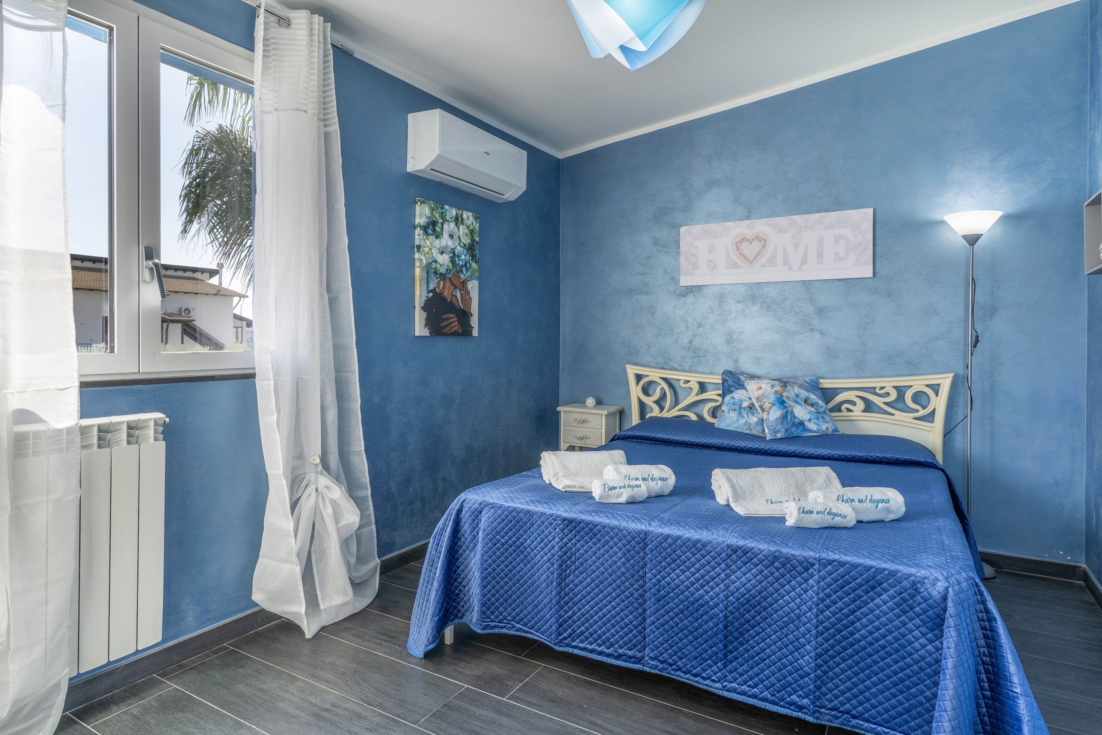 Ein Schlafzimmer mit einem Bett, einem Nachttisch, einer Wand-Klimaanlage, einem Fenster mit Blick und einem Schild mit der Aufschrift 'HOME'.