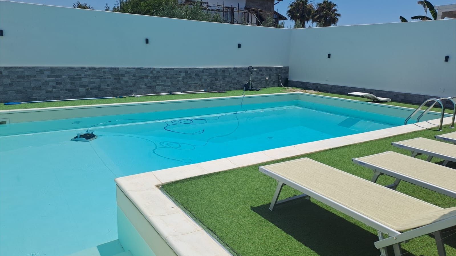 A swimming pool with a tiled deck and lounge chairs.