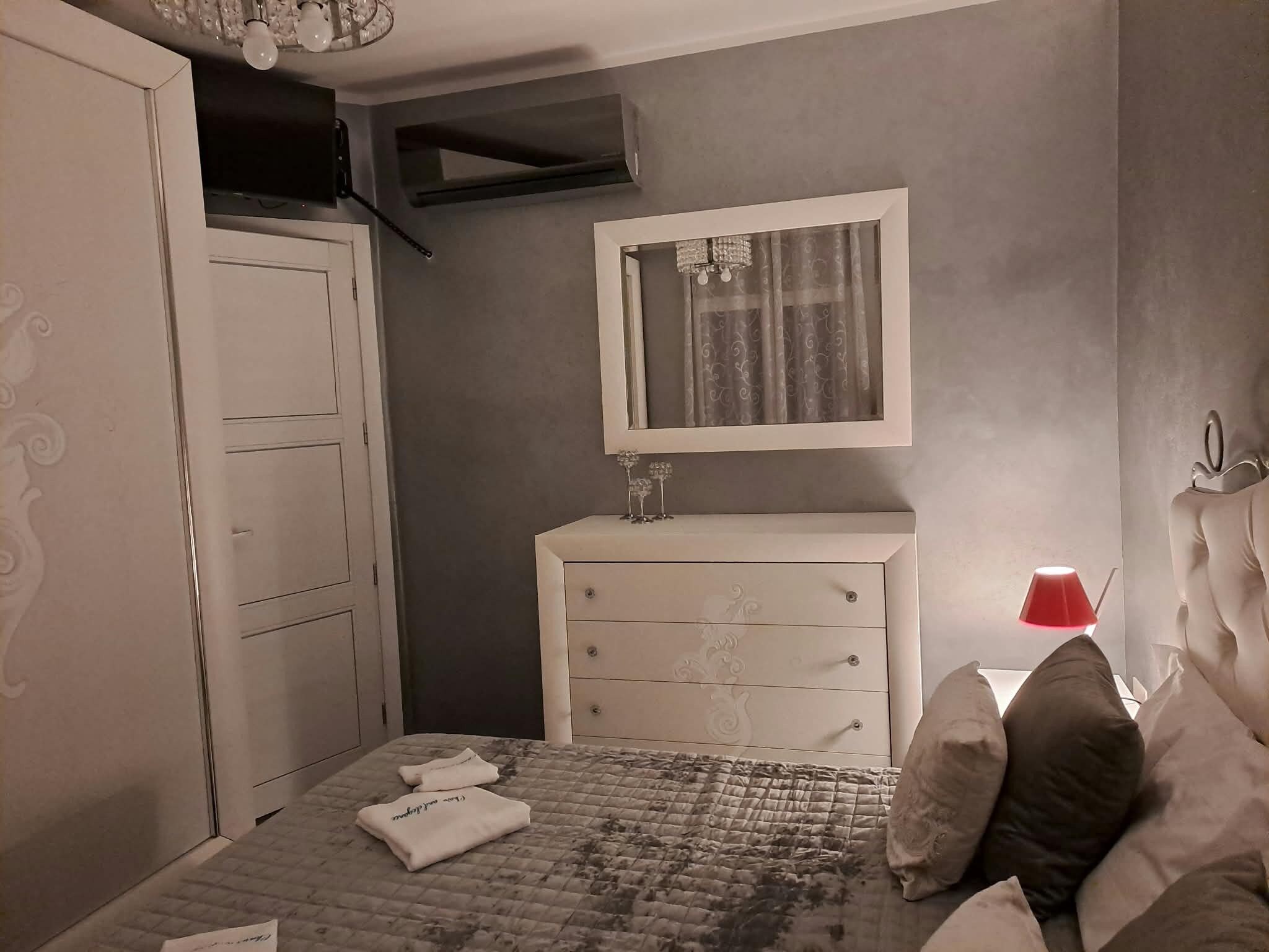 A bedroom with a bed, a dresser, a mirror, and a red lamp.