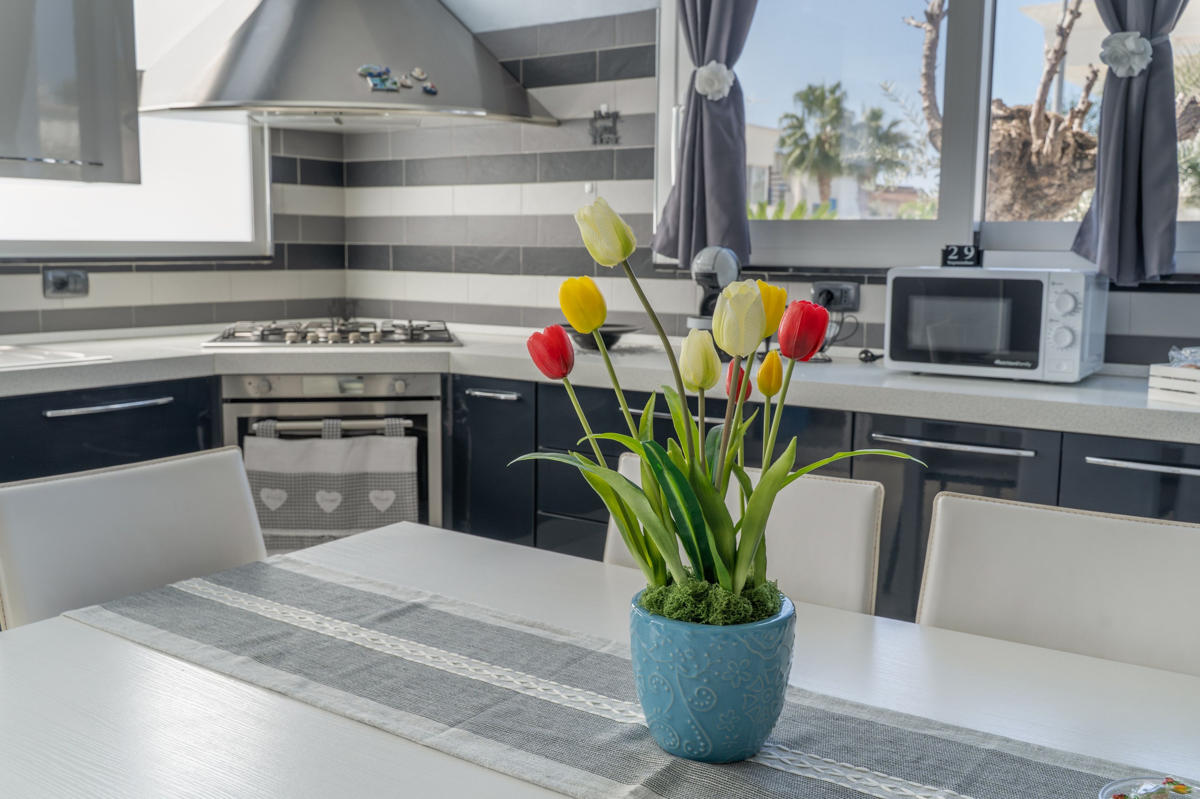 Une cuisine moderne équipée d’une cuisinière à gaz, d’un four à micro-ondes et d’un coin repas avec une table et des chaises.