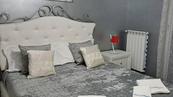 A bedroom with a tufted headboard, a bedside table with a red lamp, and a radiator.