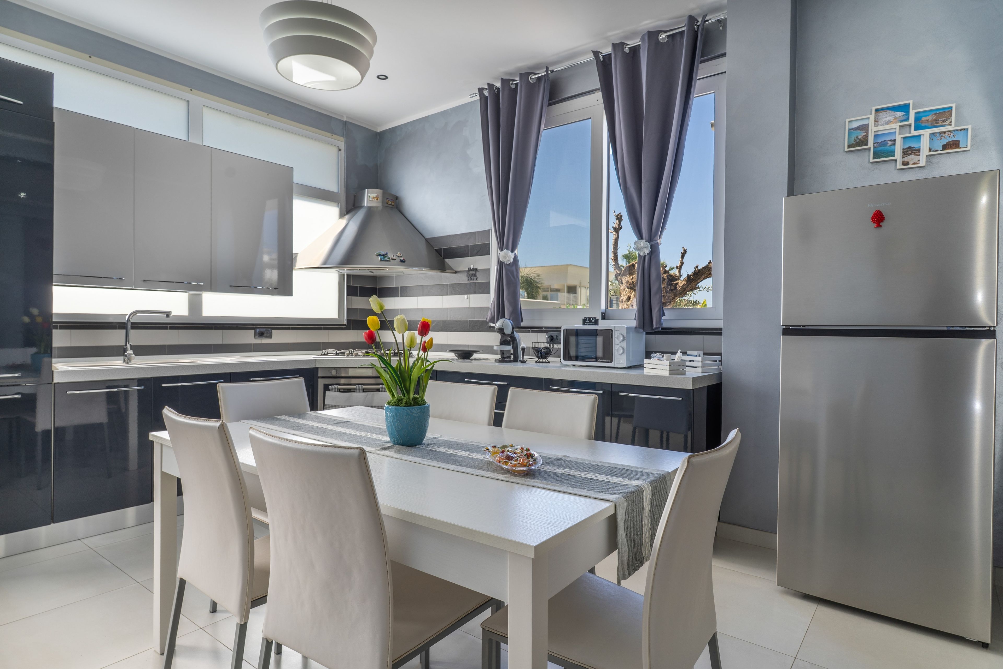 A modern kitchen with a dining area, stainless steel appliances, and a view of the outdoors.