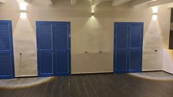 A room with a wooden floor, three blue doors, and wall-mounted lights.