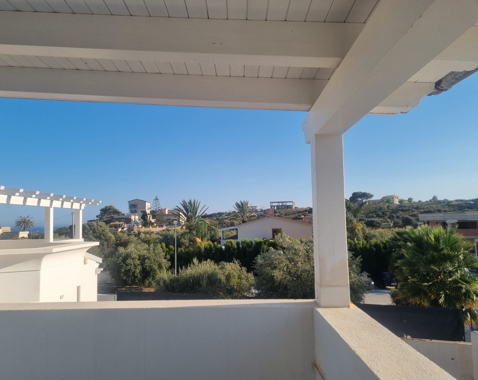Ein Balkon mit Blick auf ein Wohngebiet, inklusive Häuser und Grünflächen.