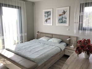 Ein modernes Schlafzimmer mit einem Bett, Nachttischen und Kunstwerken an der Wand.