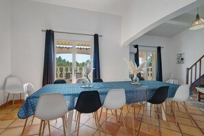A dining area with a table set for six, chairs, a view through a window, and a staircase. - Villa 'L'escale Au Soleil' with Private Pool, Wi-Fi and Air Conditioning (Montauroux)