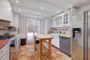 A kitchen with a wooden table, stainless steel appliances, and a tiled floor. - Villa 'L'escale Au Soleil' with Private Pool, Wi-Fi and Air Conditioning (Montauroux)