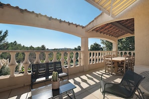 An outdoor patio with a table and chairs, a potted plant, and a view of the surrounding landscape. - Villa 'L'escale Au Soleil' with Private Pool, Wi-Fi and Air Conditioning (Montauroux)