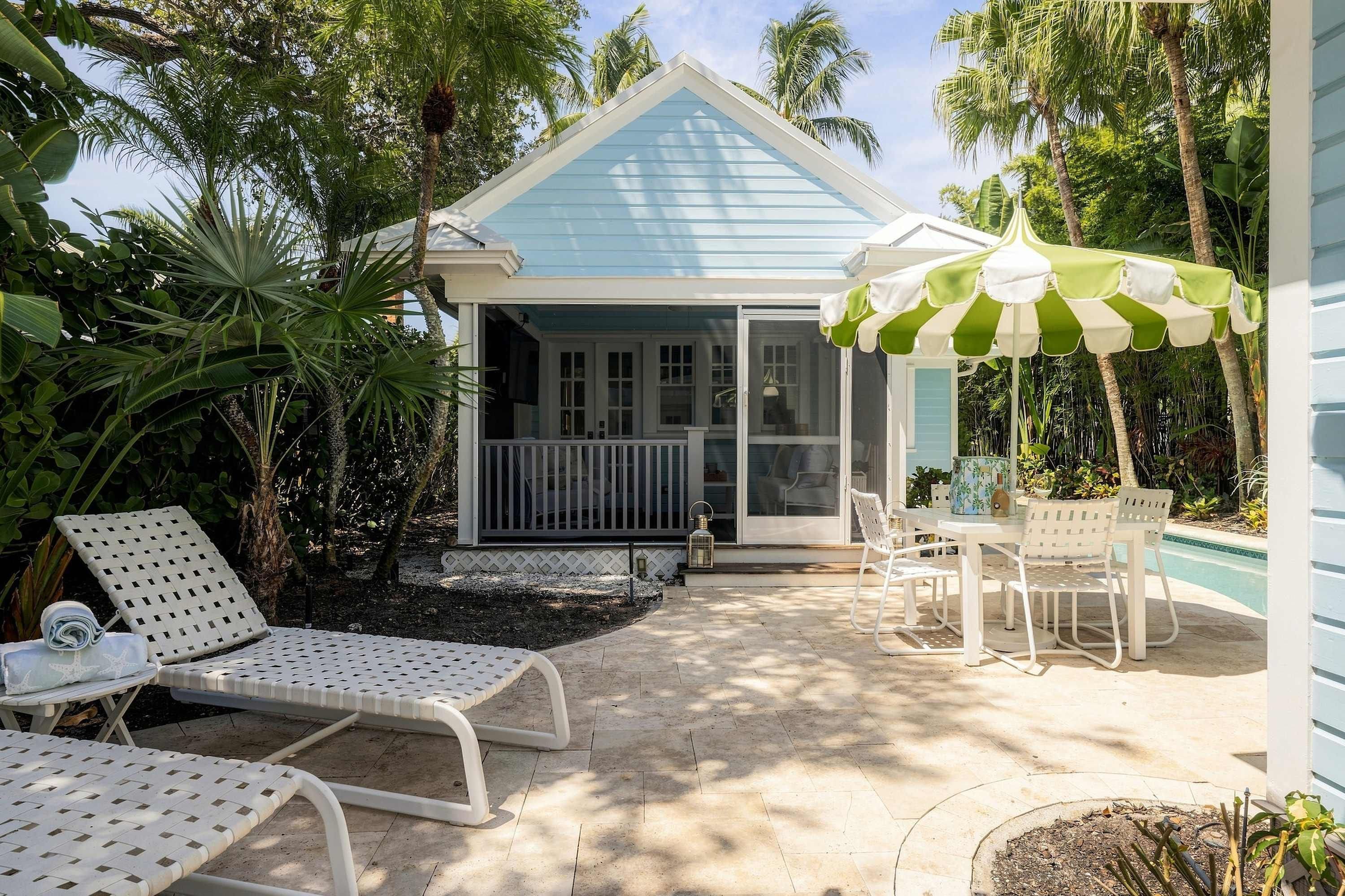 A covered outdoor area with lounge chairs, a table, and an umbrella.