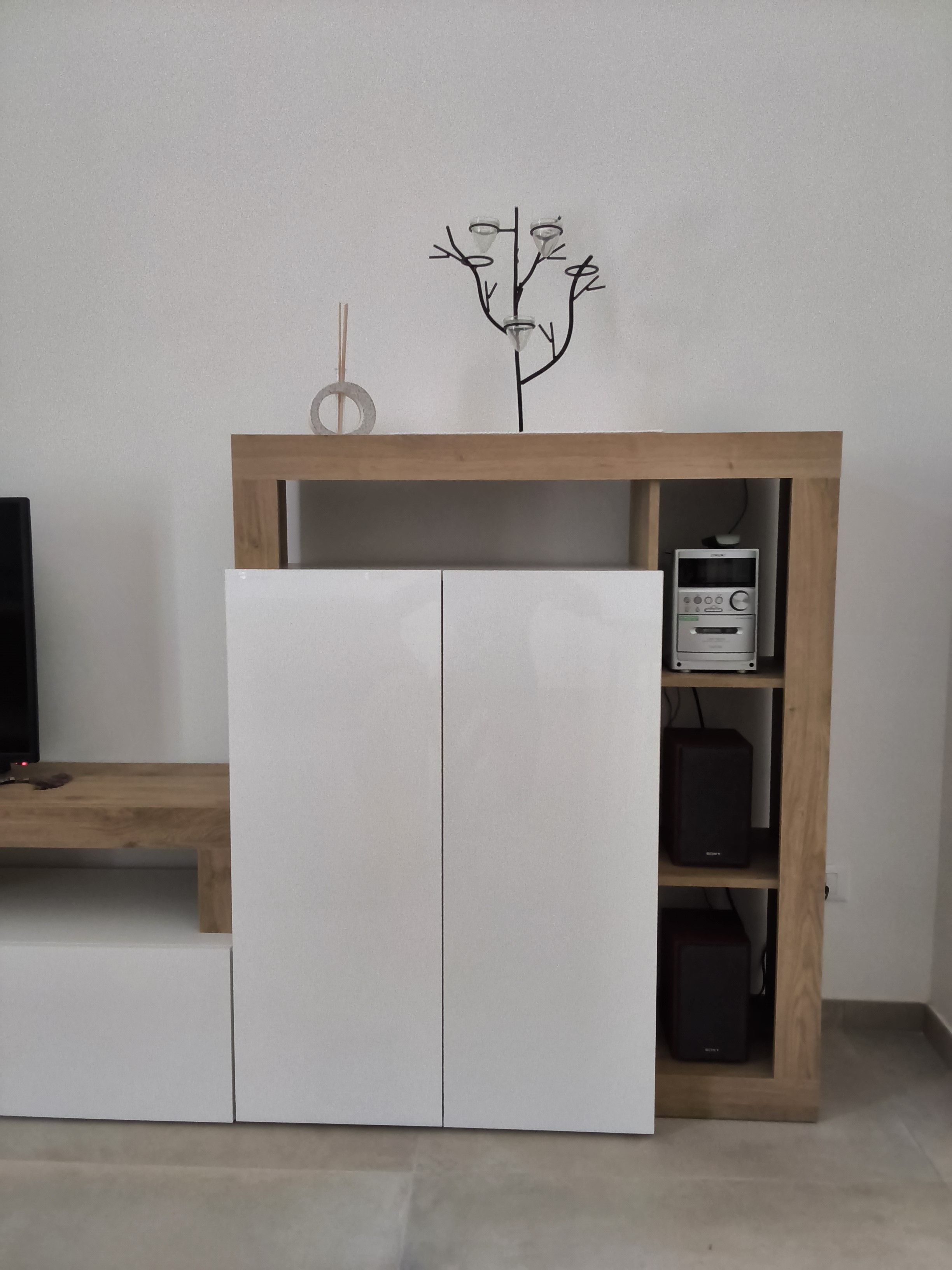 A white cabinet with a wooden top shelf, a small decorative tree, and a Sony audio system on the right.