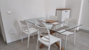 Ein stilvoller Essbereich mit einem Glastisch, weißen Stühlen und einem Holzschrank.