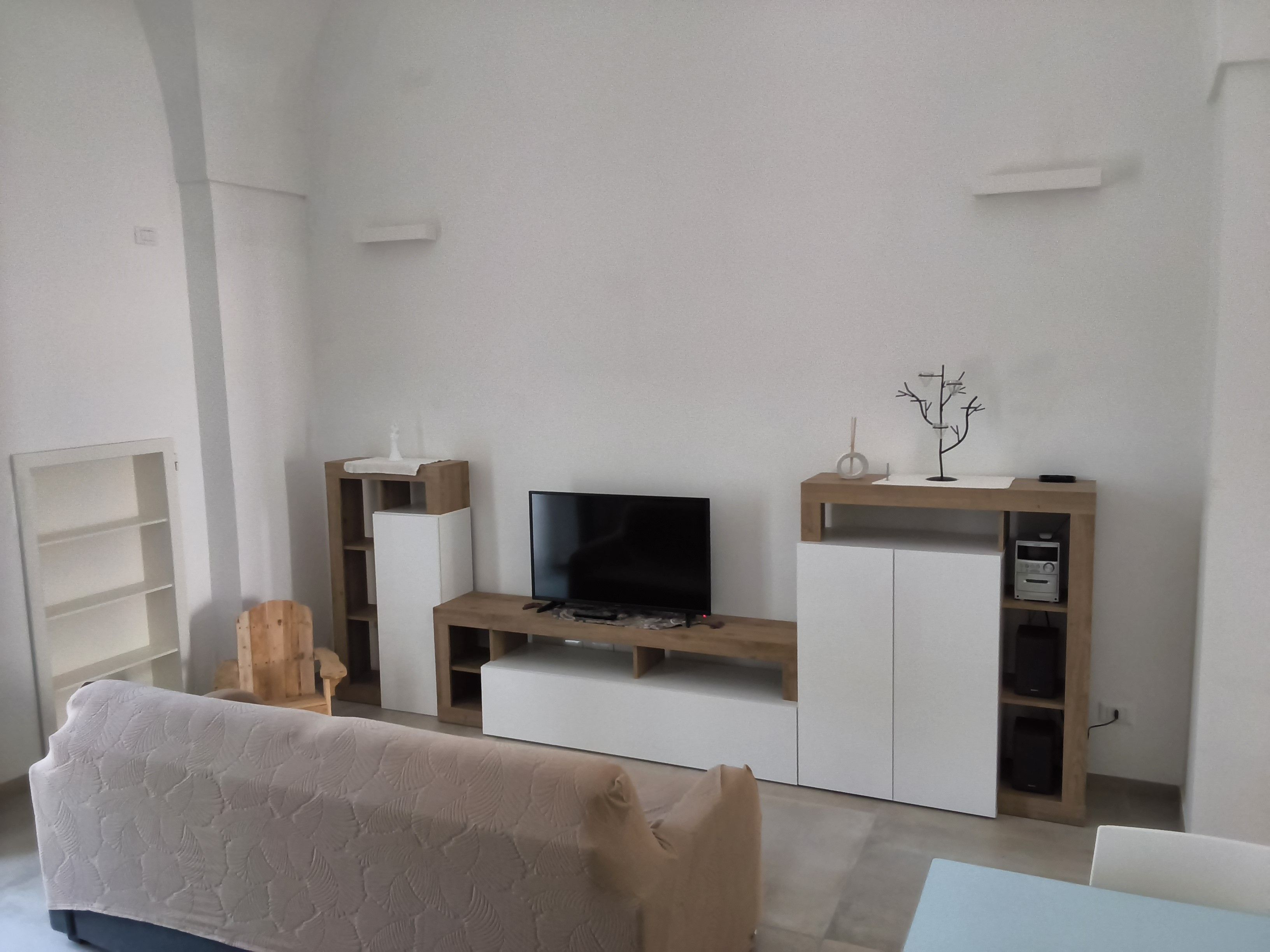 A modern living room with a flat-screen TV, wooden entertainment unit, and a sofa.