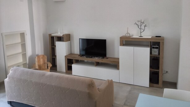 Ein modernes Wohnzimmer mit Flachbildfernseher, einer Holzunterhaltungseinheit und einem Sofa.