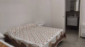 A bedroom with a bed, a bedside table, a wardrobe, and a bathroom visible through an open door.