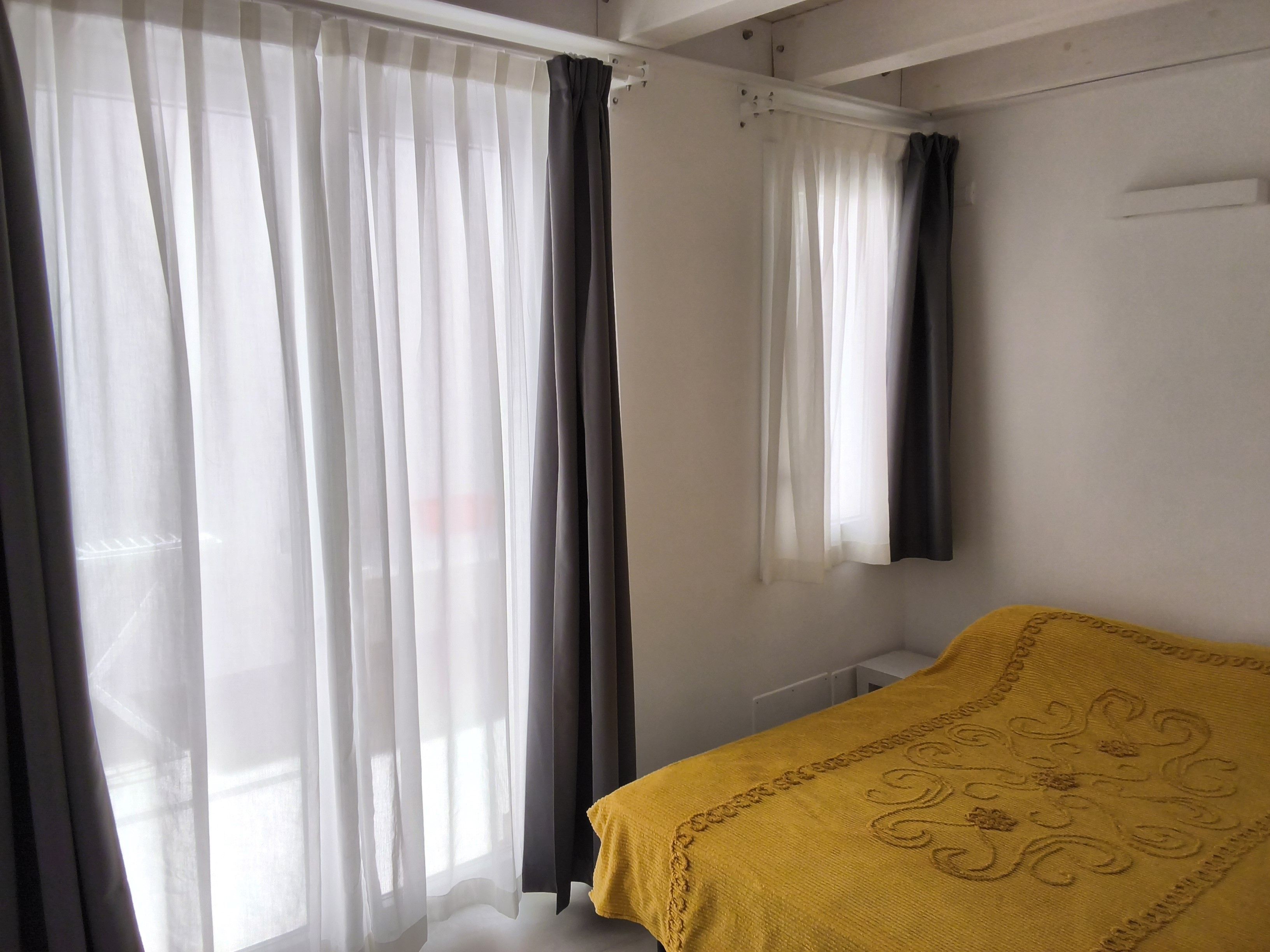 A bedroom with a bed, curtains, and a window.