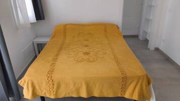 Ein Bett mit einer gelben, strukturierten Tagesdecke und einer dekorativen Kante.