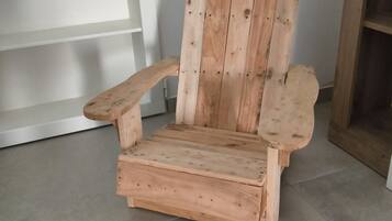 Ein hölzerner Adirondack-Stuhl mit Armlehnen und hoher Rückenlehne, auf einem gefliesten Boden platziert.
