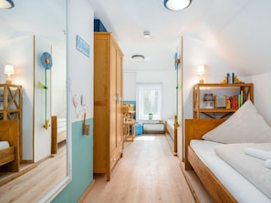A room with a wooden bed, a bookshelf, a desk, and a window. - Holiday Home in Upleward With Sauna (Krummhoern)