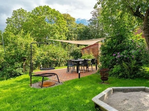 A patio area with a table and chairs, surrounded by lush greenery and a brick wall. - Holiday Home in Upleward With Sauna (Krummhoern)