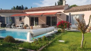 Ein Wohnhaus mit Schwimmbad, Sitzgelegenheiten im Freien und einem Garten.
