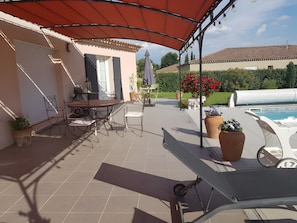 A covered patio area with a table and chairs, a pool, and potted plants. - Bed and Breakfast 'Chambre Cézanne' with Mountain View, Shared Pool and Air Conditioning (Saumane de Vaucluse)