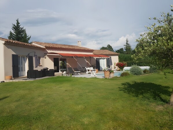 A house with a covered patio, outdoor seating, and a swimming pool. - Bed and Breakfast 'Chambre Cézanne' with Mountain View, Shared Pool and Air Conditioning (Saumane de Vaucluse)