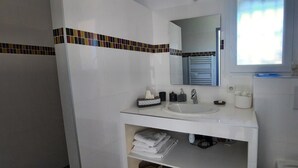 Ein Badezimmer mit weißem Waschbecken, Spiegel und Ablage für Handtücher.