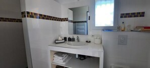 A bathroom with a white sink, mirror, and towel storage. - Bed and Breakfast 'Chambre Cézanne' with Mountain View, Shared Pool and Air Conditioning (Saumane de Vaucluse)