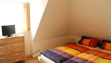 Un dormitorio con una cama, un televisor en una cómoda y una ventana.