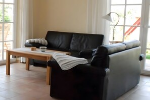 Una sala de estar moderna con un sofá de cuero negro, una mesa de centro de madera y una lámpara de pie.