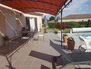 A covered patio area with a table and chairs, a pool, and potted plants. - Bed and Breakfast 'Chambre Modigliani' with Mountain View, Wi-Fi and Air Conditioning (Saumane de Vaucluse)