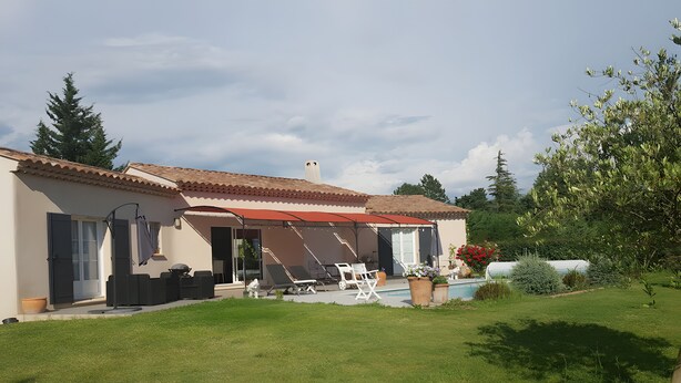 Ein Haus mit überdachter Terrasse, Sitzgelegenheiten im Freien und einem Swimmingpool.