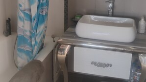 Ett badrum med ett vitt handfat, en spegel ovanför och en duschdraperi med blått mönster.