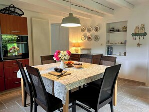 A dining area with a marble table, dark chairs, a vase of flowers, and a hanging light fixture. - Old Jura farmhouse in the heart of the Haut-Jura (Châtel-de-Joux)