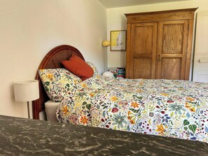 A bedroom with a bed, a wooden wardrobe, a bedside lamp, and a wall-mounted picture. - Old Jura farmhouse in the heart of the Haut-Jura (Châtel-de-Joux)