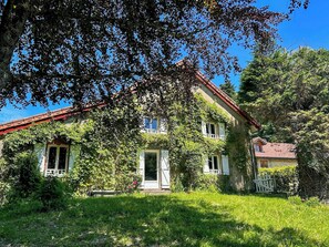 A two-story house with a red roof, surrounded by lush greenery and trees. - Old Jura farmhouse in the heart of the Haut-Jura (Châtel-de-Joux)