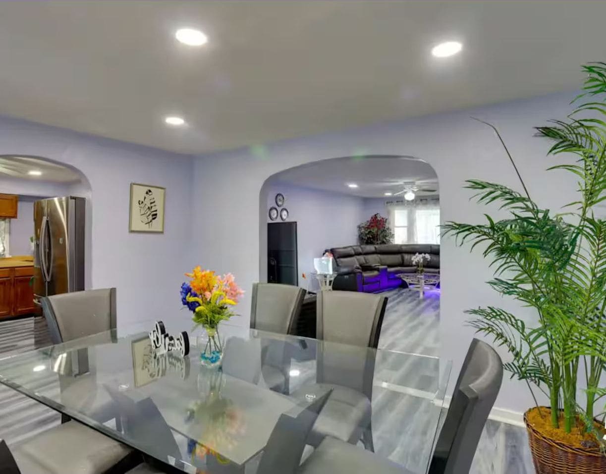 A dining space with a glass table opens to the kitchen and living room through arched doorways.