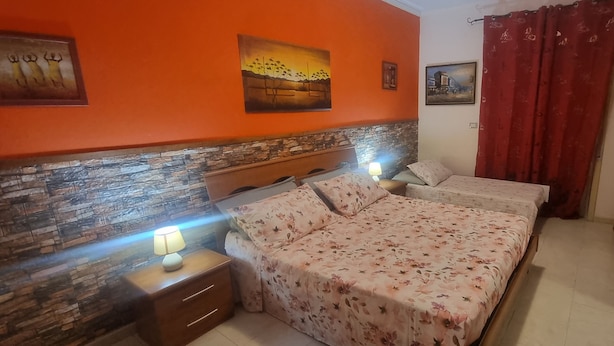 A bedroom with a double bed, a nightstand with a lamp, and a stone wall. - Apartment 'Casa in Complesso Sonia' with Private Terrace (Santa Teresa di Riva)