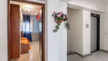 A hotel room with a bed, a bathroom, and a hallway leading to an elevator.
