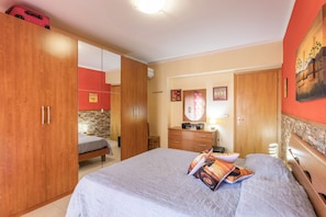 A bedroom with a bed, a wardrobe, a dresser, and a mirror.