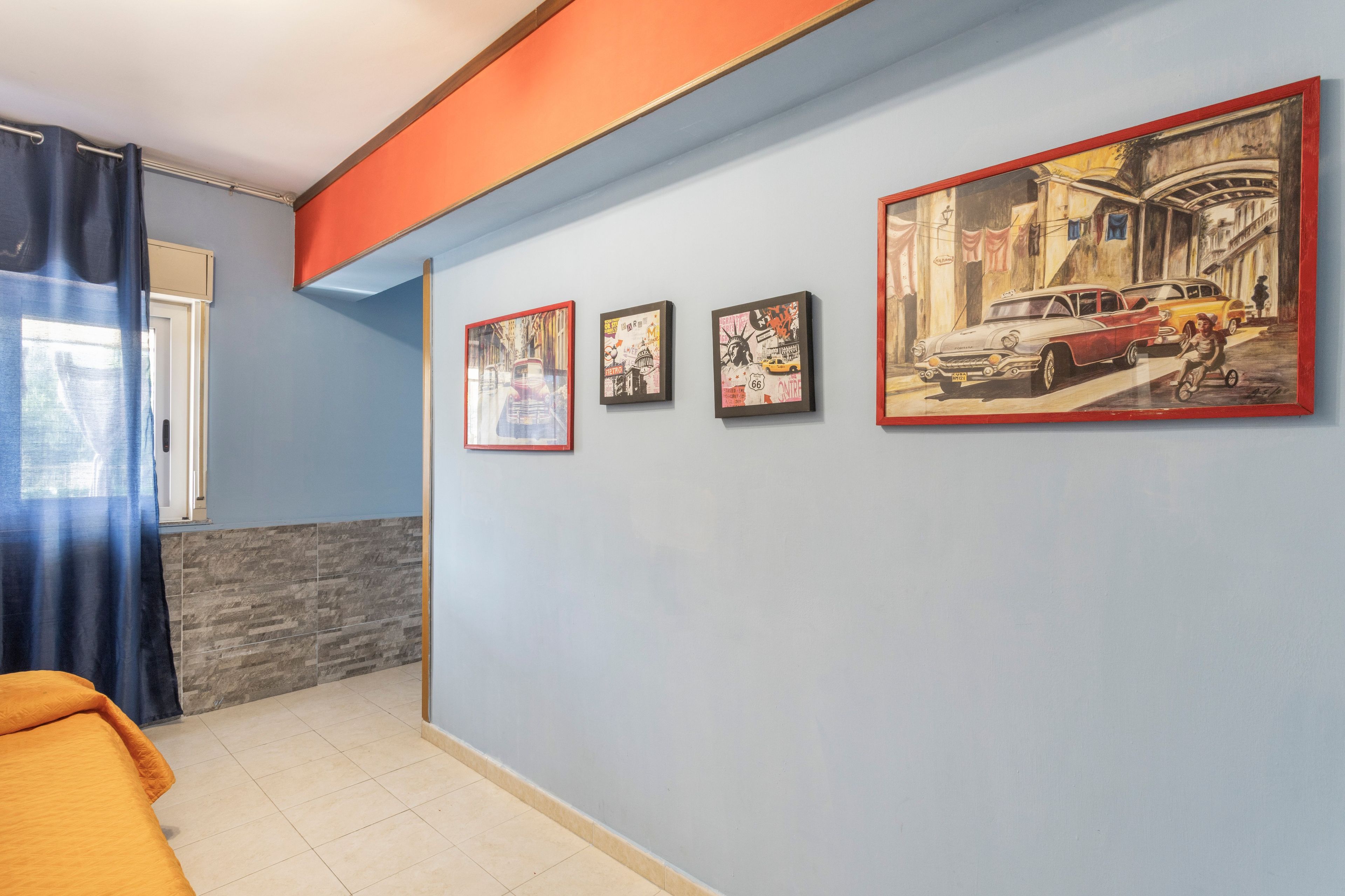 Een hotelkamer met een bed, een raam met gordijnen en drie ingelijste foto's aan de muur.