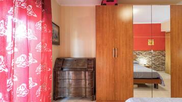 A bedroom with a bed, a wardrobe, a dresser, and a red curtain.