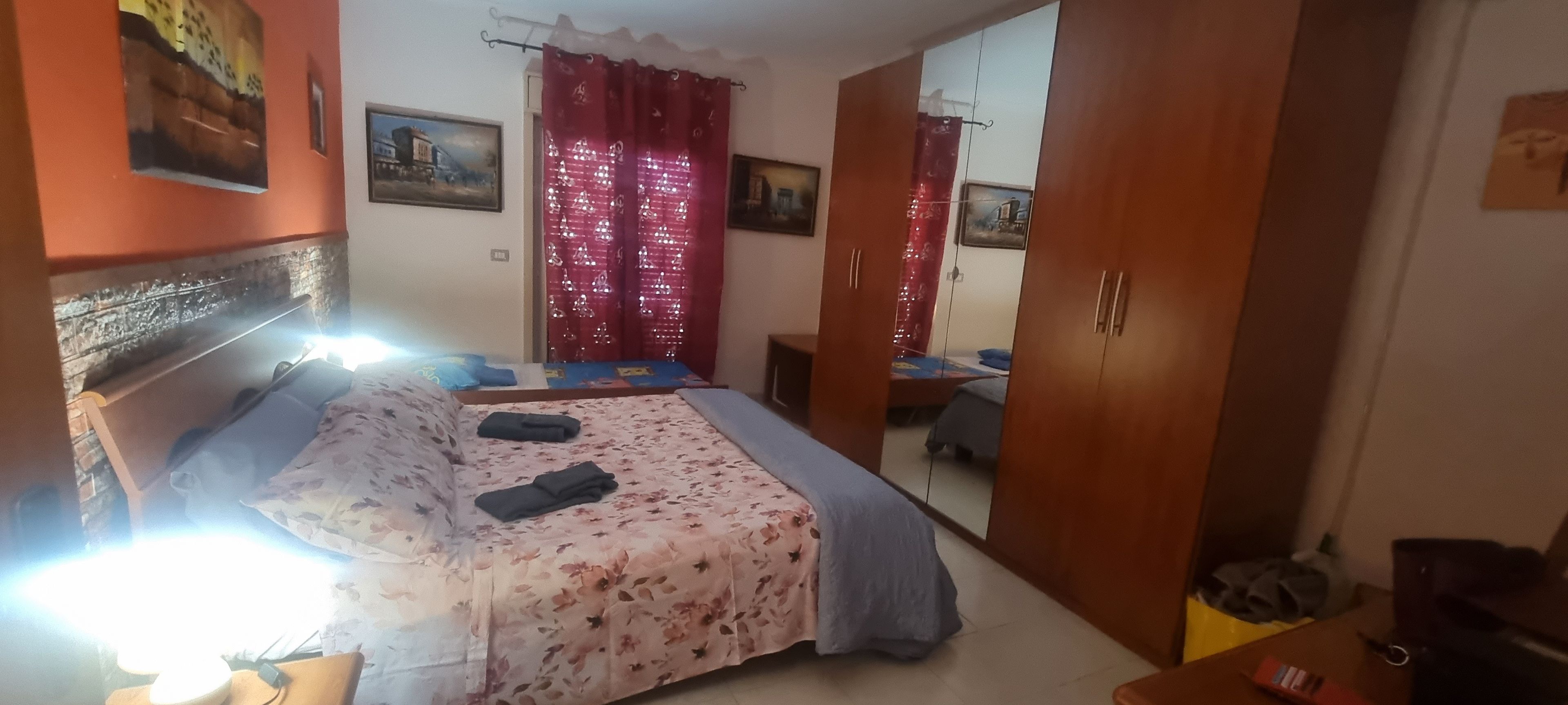 Ein Schlafzimmer mit Bett, Kleiderschrank, Schreibtisch und Spiegel.